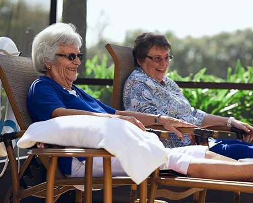 Two smiling residents relaxing outdoors by the pool