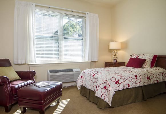 A cozy resident room with a bed and armchair