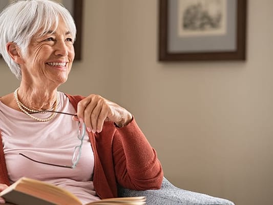Senior woman reading a book in a cozy living room
