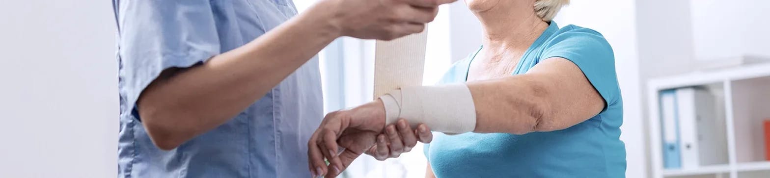 Nurse assisting a senior with a bandage on her arm