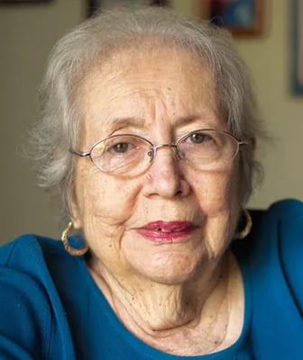 An elderly woman smiling with glasses