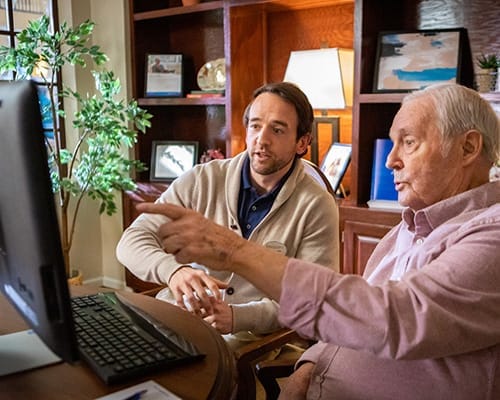 Staff assisting a resident with a computer in a common area