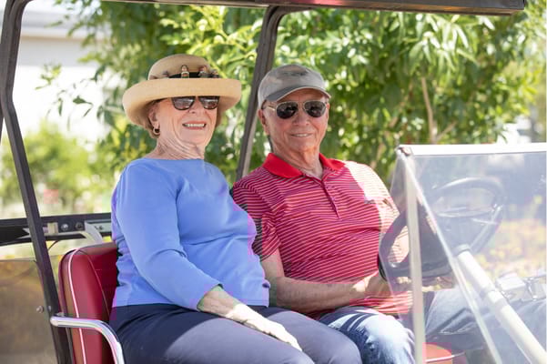 Two residents enjoying a golf cart ride outdoors