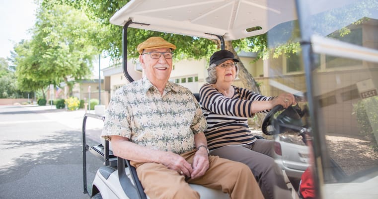 Residents enjoying a ride in a golf cart outside