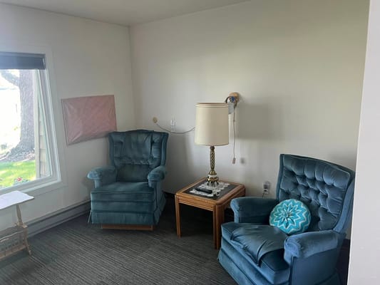 Two blue armchairs with a lamp and table in a living room