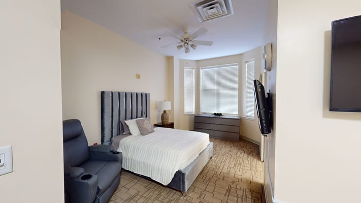 Private bedroom with a bed, chair, and window.