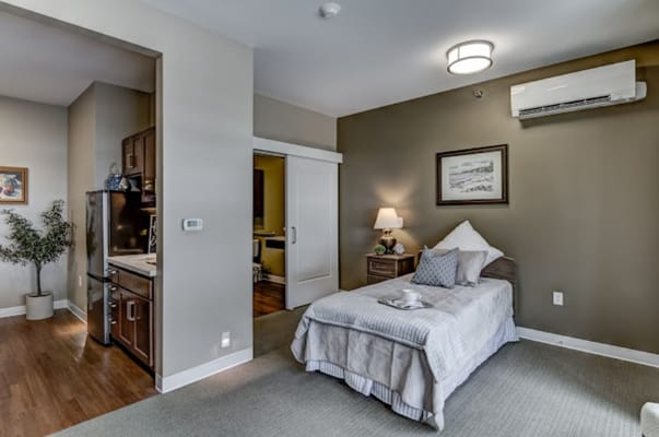 Cozy bedroom in a senior living facility with light decor and modern amenities.