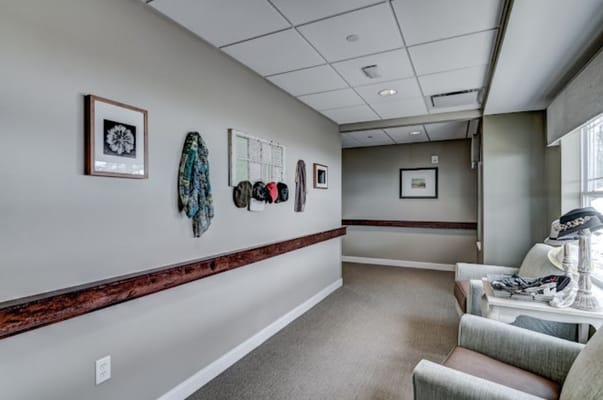 A hallway adorned with wall art and scarves, featuring a seating area.
