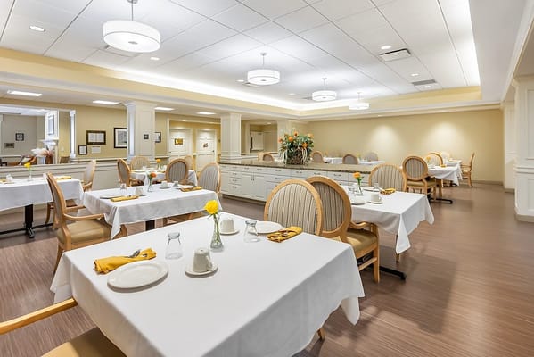Bright and spacious dining area with tables set for residents