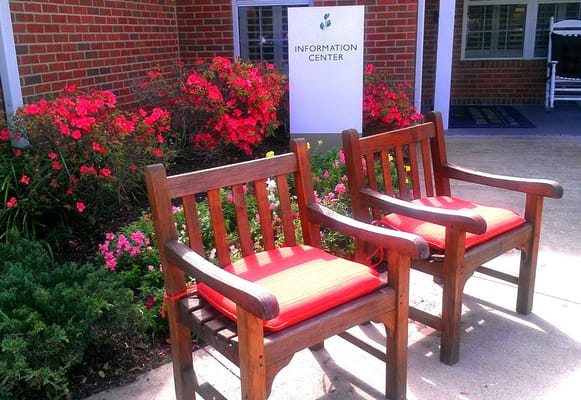 Outdoor seating area with flowers and an information center sign