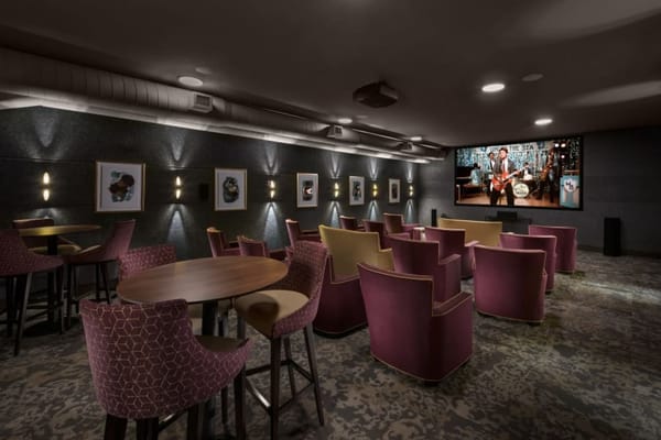 Cozy theater room with purple seating and a large screen showing a performance.