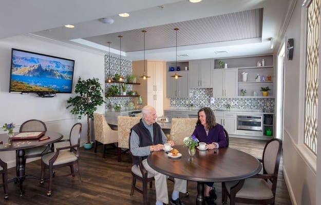 Two residents enjoying coffee and conversation in the common area kitchen.