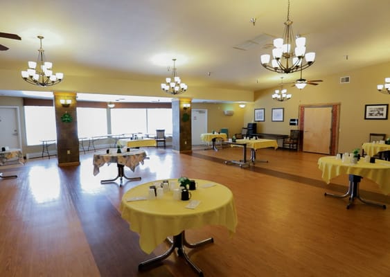 Spacious dining room with yellow tables and warm lighting.