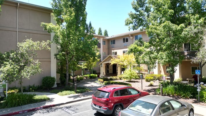 Exterior view of Atria Carmichael Oaks with greenery