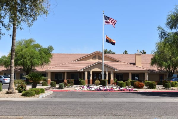 Exterior view of a senior living facility with flower beds.