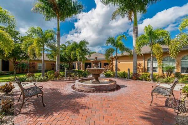 Outdoor fountain surrounded by palm trees and seating area.
