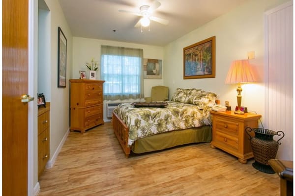 A well-furnished bedroom with a bed, dresser, and lamp.