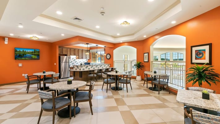 Brightly decorated dining area with tables and a kitchen.