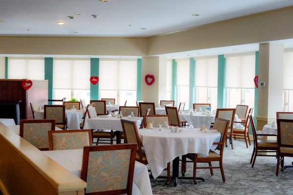 A well-lit dining area with tables set for residents