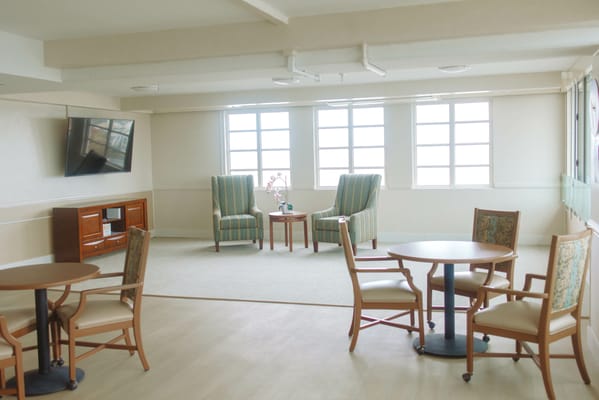 Cozy lounge with seating and a TV in a senior living facility