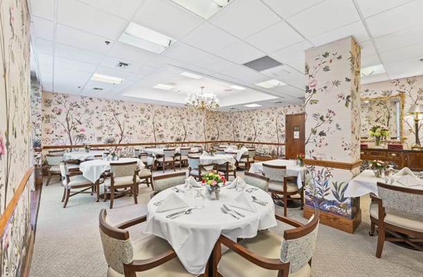 Elegant dining room with floral wallpaper and tables set for meals