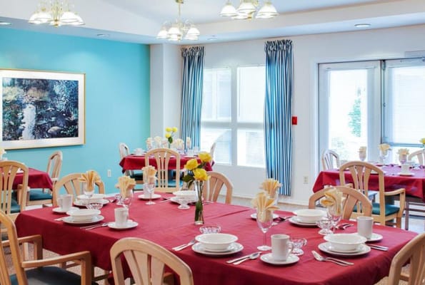 Well-decorated dining room with red tablecloths and floral centerpieces