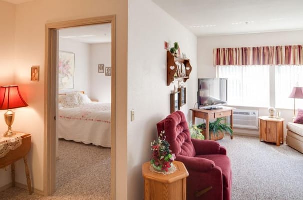 Living room with a comfortable chair and a view into the bedroom