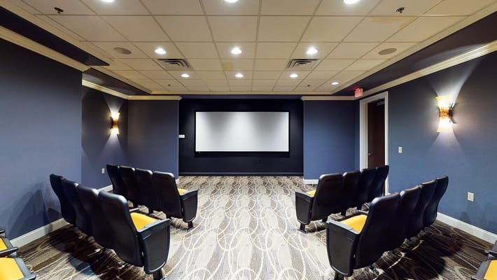 Theater room with seating and a large screen at Total Rehab at Moorestown.