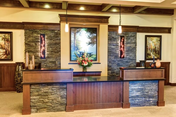 Modern reception desk with stone accents and floral arrangement.