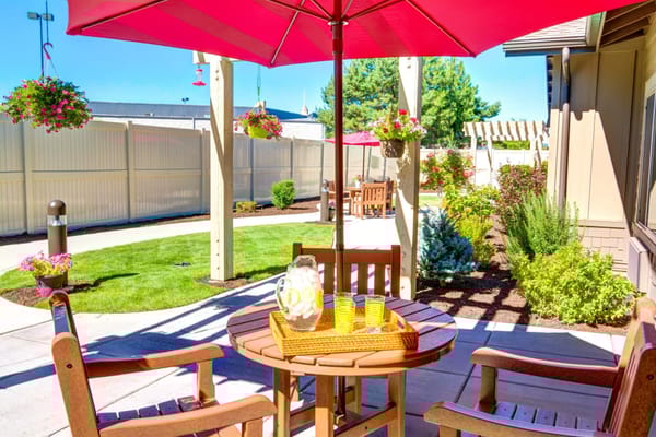 Outdoor seating area with wooden chairs and table under a red umbrella