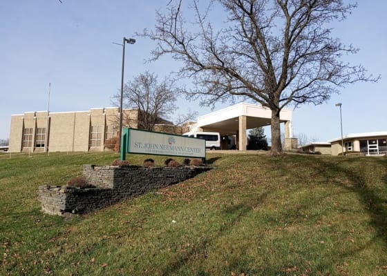 Signage at the entrance of St. John Neumann Center with the facility building in the background