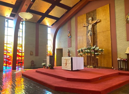 Interior view of the chapel featuring a wooden crucifix and stained glass windows.