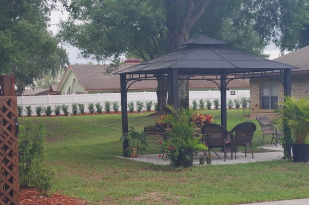 Outdoor gazebo with seating area in a landscaped garden