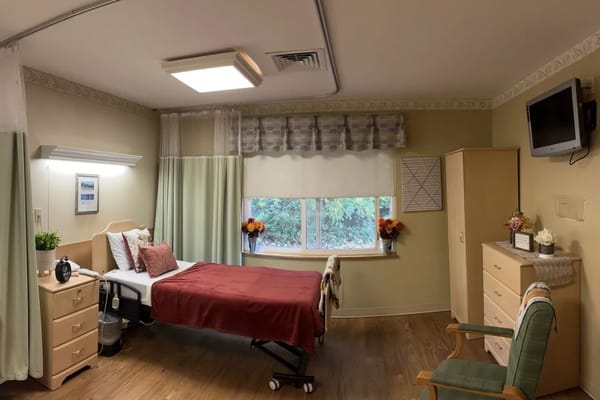 Cozy private room with a bed, dresser, and window at Pelican Pointe.