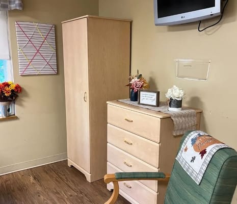 Interior of a cozy room featuring a wardrobe, dresser, and flowers.