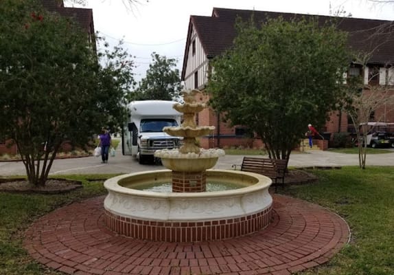 A fountain in a courtyard with a van and staff members
