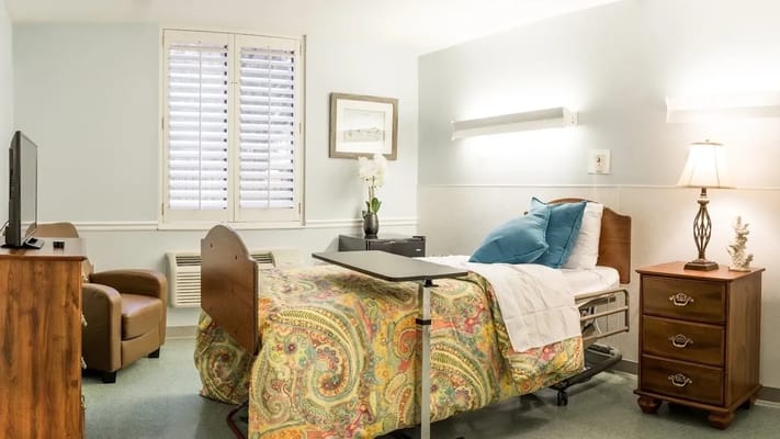 A cozy, well-decorated bedroom featuring a hospital bed, nightstand, and comfortable seating.