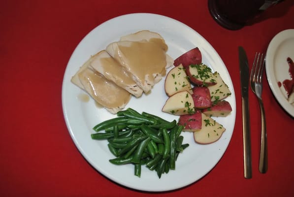 A plate of turkey with green beans and potatoes