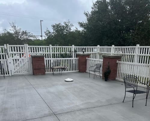 Patio area with benches and chairs surrounded by a white fence