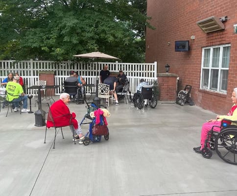 Residents socializing outdoors in wheelchairs on a patio