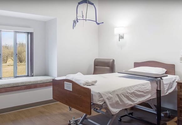 Patient room with a bed, chair, and window