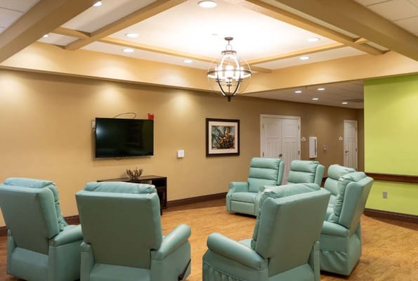 Spacious lounge with green recliners and a television
