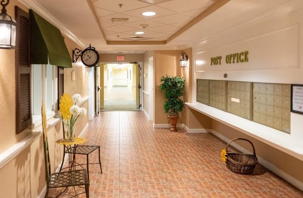 Interior hallway leading to the post office with a clock and decorative plants.