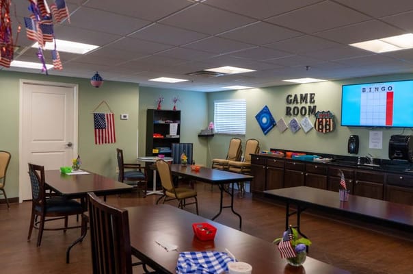 Brightly lit game room with tables and chairs set up for activities.