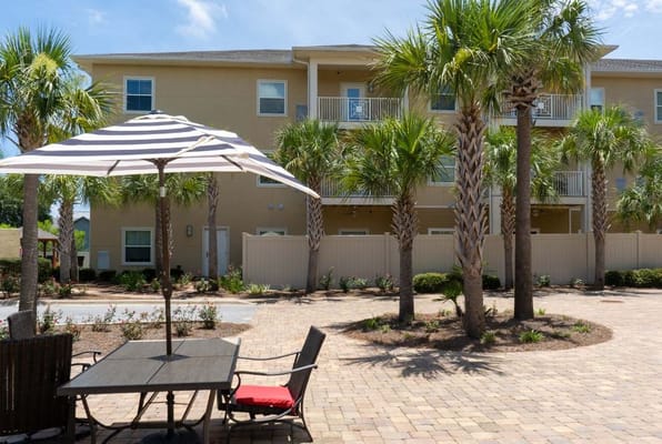 Outdoor seating area with a striped umbrella and palm trees
