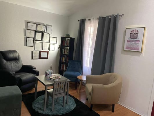 Lounge area with chairs, table, and wall of framed documents