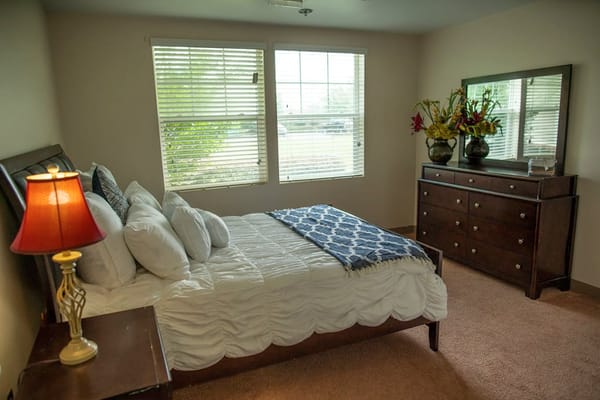 Cozy bedroom featuring a bed, dresser, and decorative flowers.