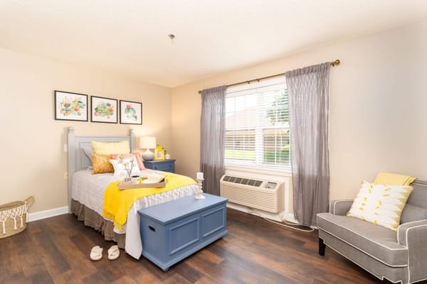 A well-decorated bedroom with a bed, nightstand, and seating area.
