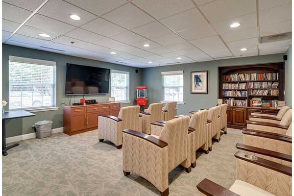 Comfortable seating area in the community room with a television and bookshelves.