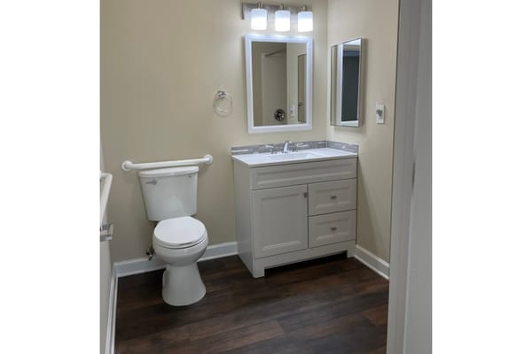 Bright bathroom featuring a sink, toilet, and large mirror
